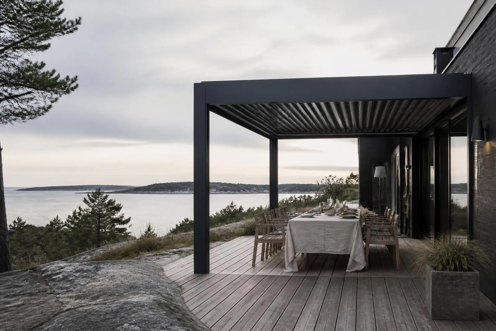 Bioklimatisk lamellpergola i antracitgrå aluminium från Tjust – Utekök & Uteliv på en altan i Västerviks skärgård